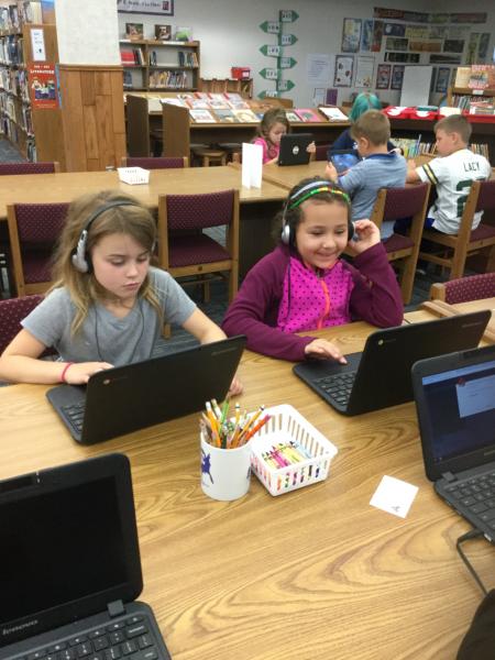 Students using computers with headphones on in the library