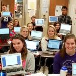 Students and teacher holding laptops with screens facing the camera